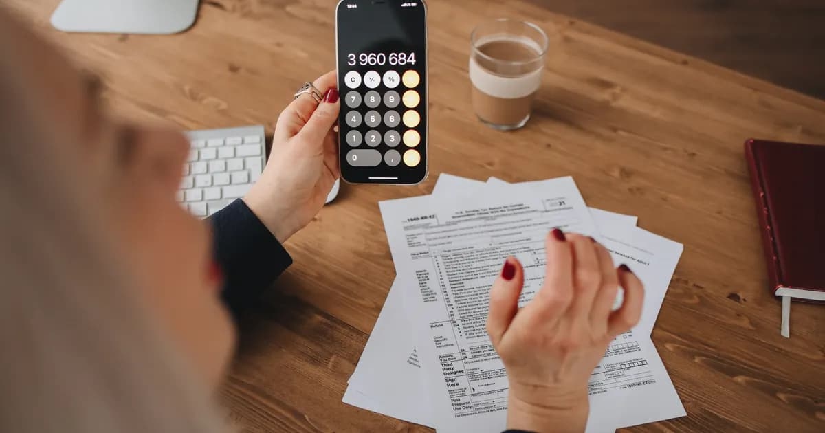 Pessoa usa calculadora no celular para revisar custos.