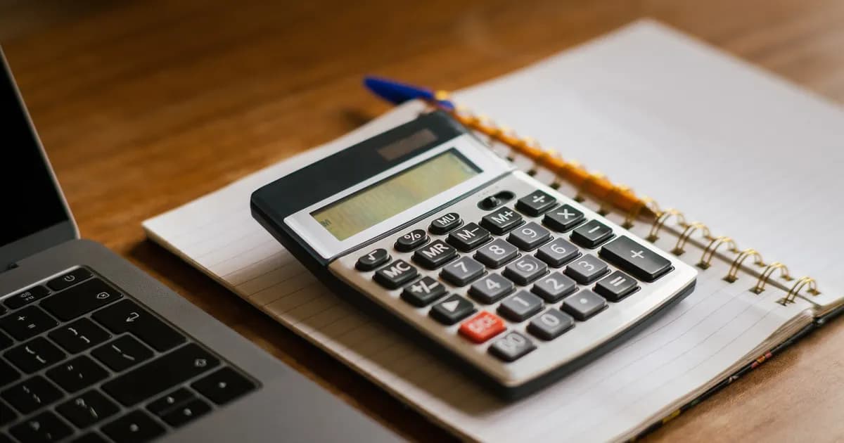 Calculadora e notebook sobre uma mesa de trabalho.