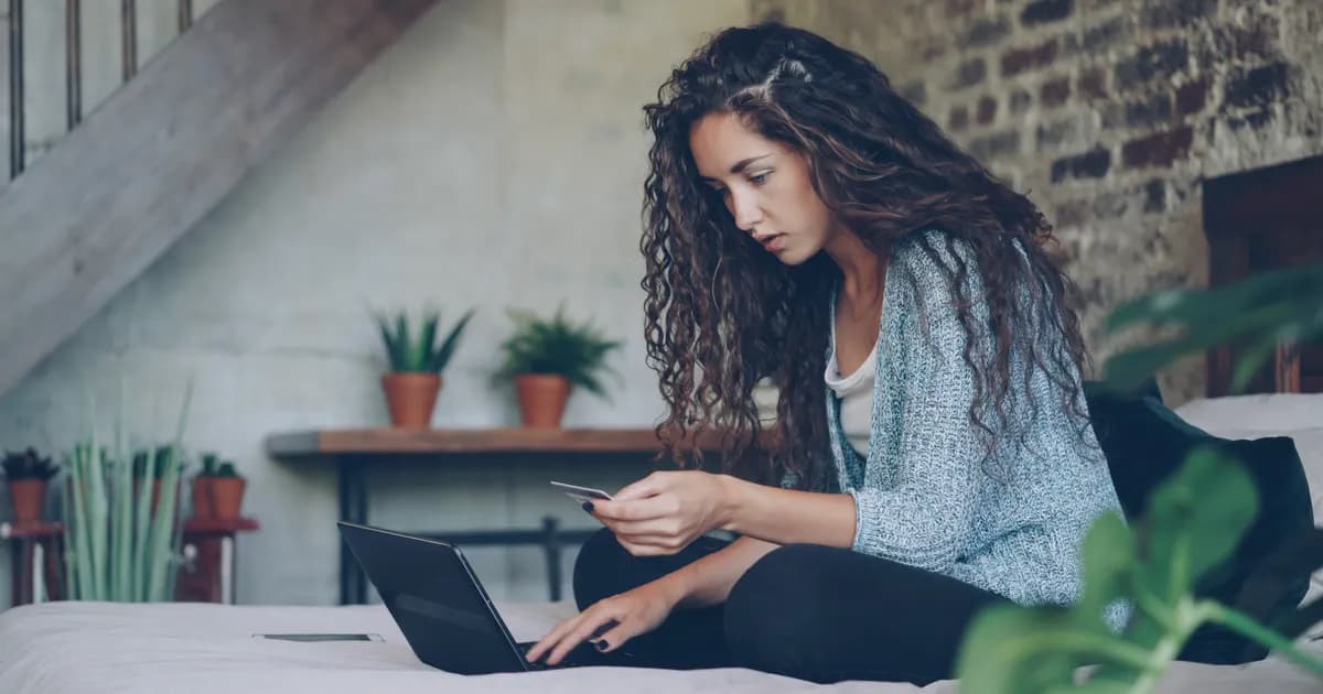 Compradora usa notebook e cartão para fazer um pedido.