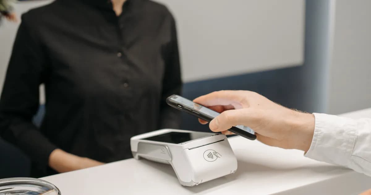 Cliente paga com smartphone em balcão comercial.