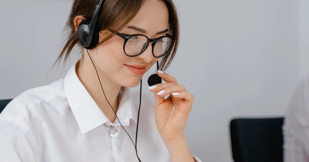Atendente usa headset e notebook para falar com clientes.